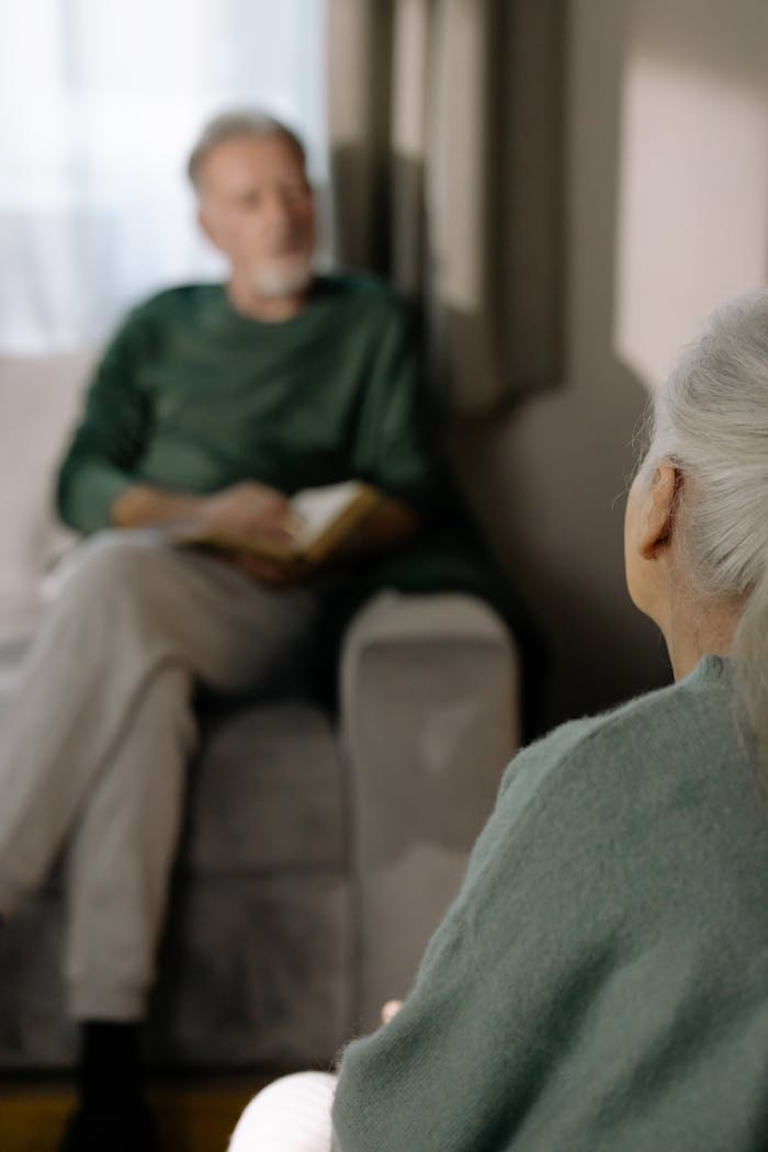 A serene moment between senior adults sitting together indoors, embracing companionship.