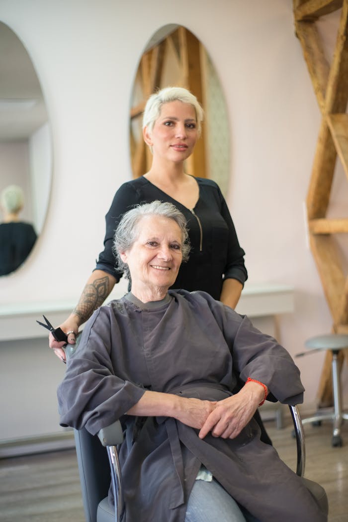 Elderly woman enjoys haircut with smiling stylist at a salon in Portugal.